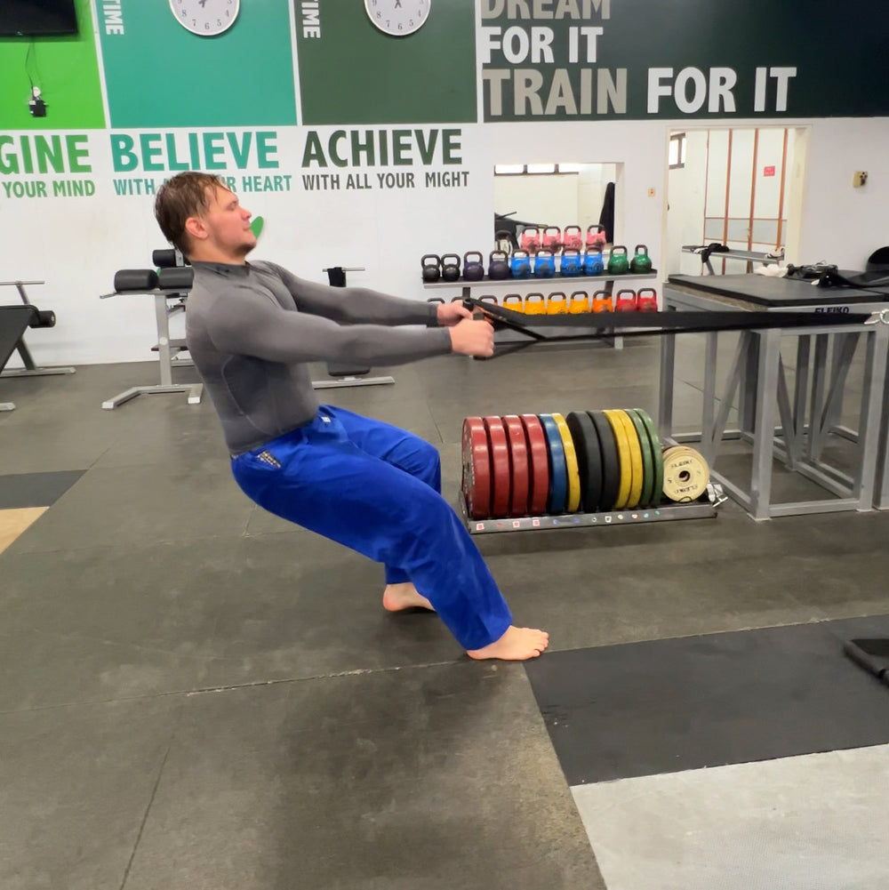 Athlete performing a seated row against Q-Tail resistance in a gym